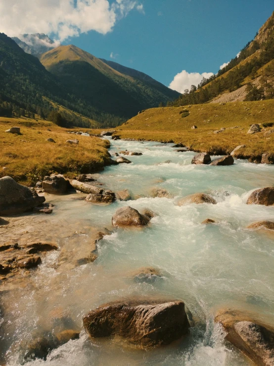 water moving through a river near mountains on a sunny day