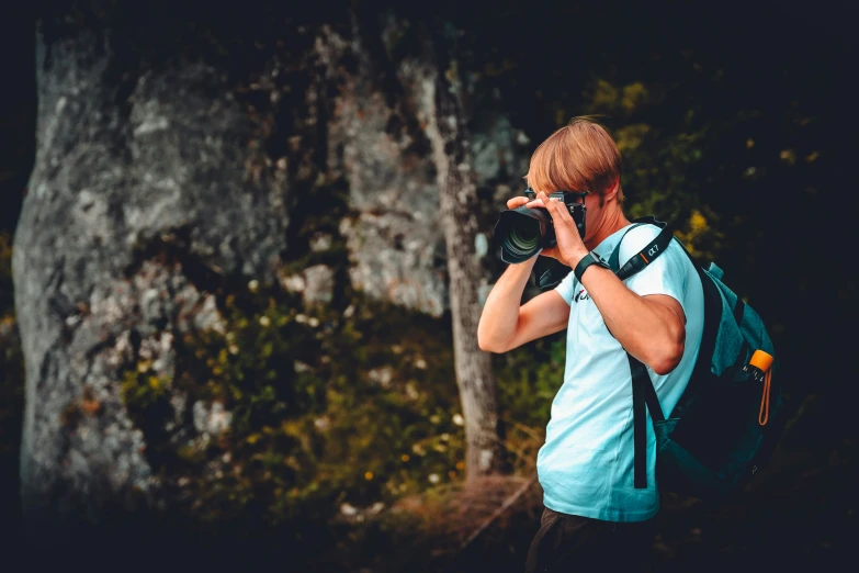 a man with backpack and camera in hand taking a po