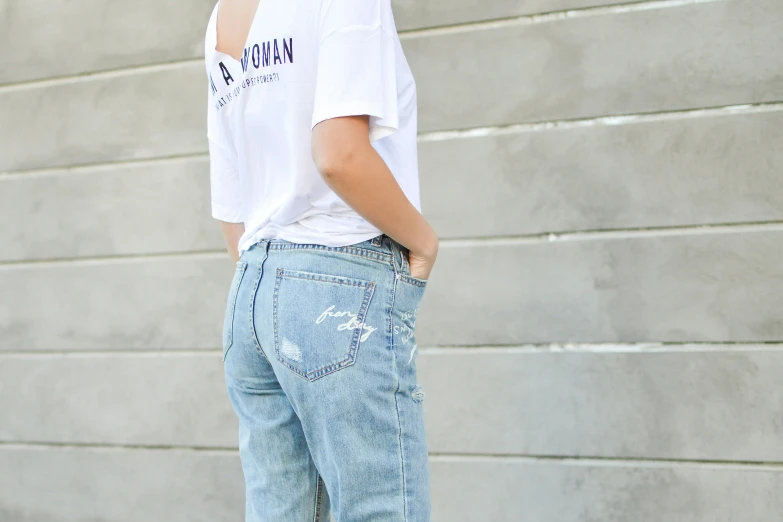 a person in white t - shirt leaning against grey wall