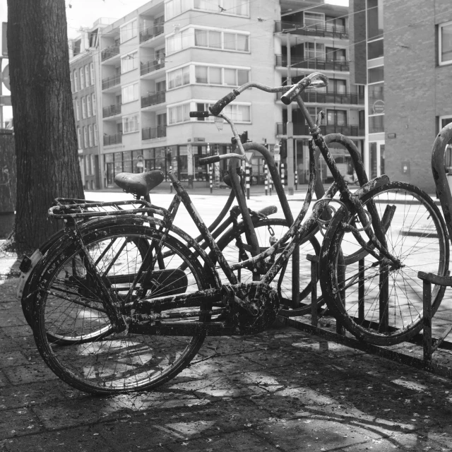 two bikes locked to the post outside a building