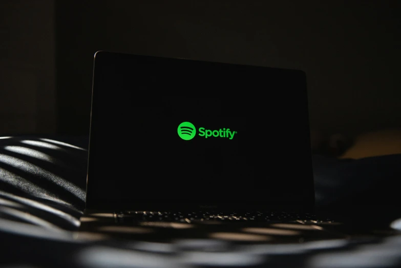 a computer with spotify sitting on top of a white table