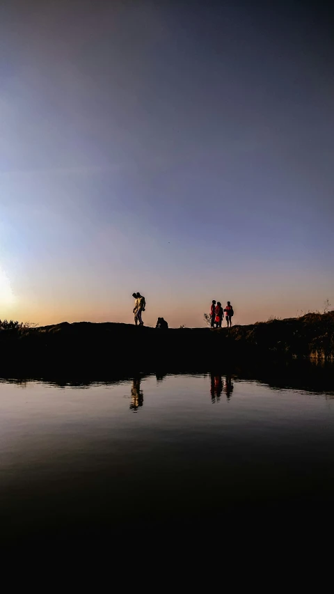 two people are standing on the shore near the water