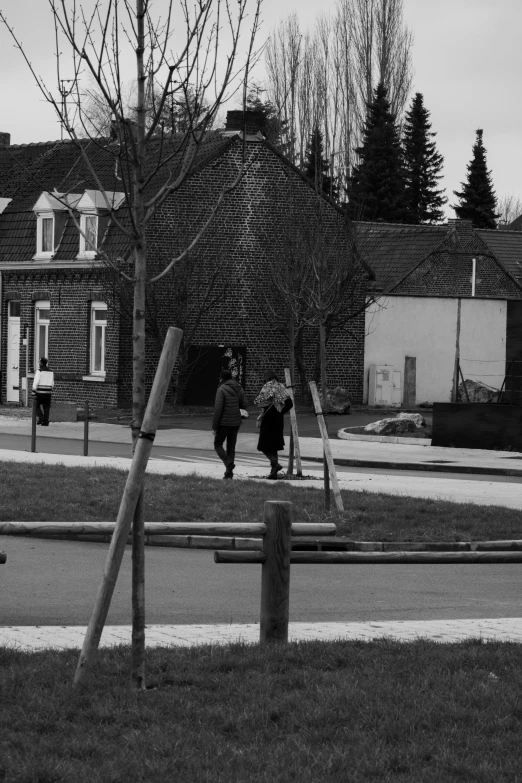 two people walking on a city street next to a fence