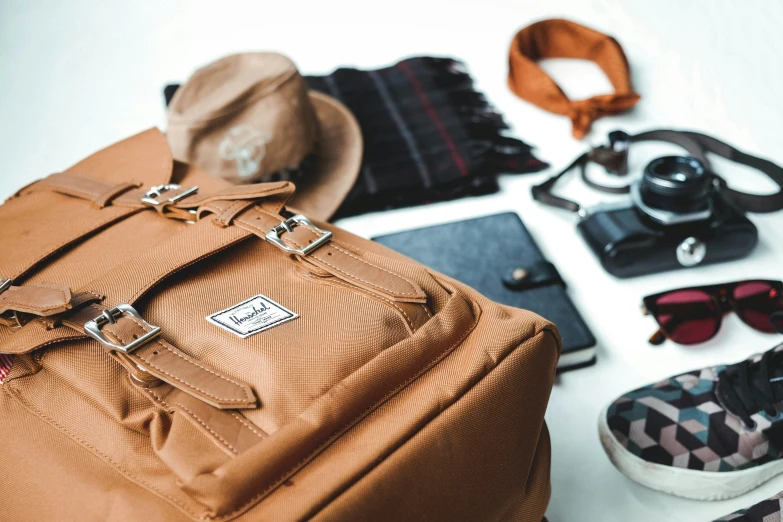 a suitcase has sunglasses, a hat and other items on it