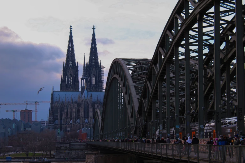 people standing on a bridge in front of a cathedral