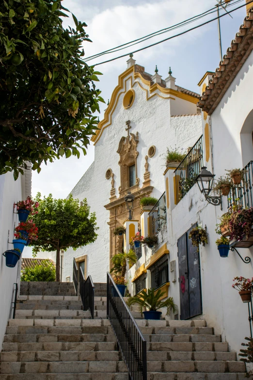 a white and yellow building that has many plants on the balcony