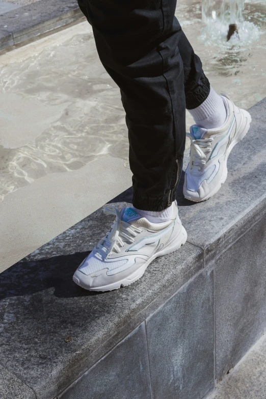 someone standing on a ledge near water with their shoes off