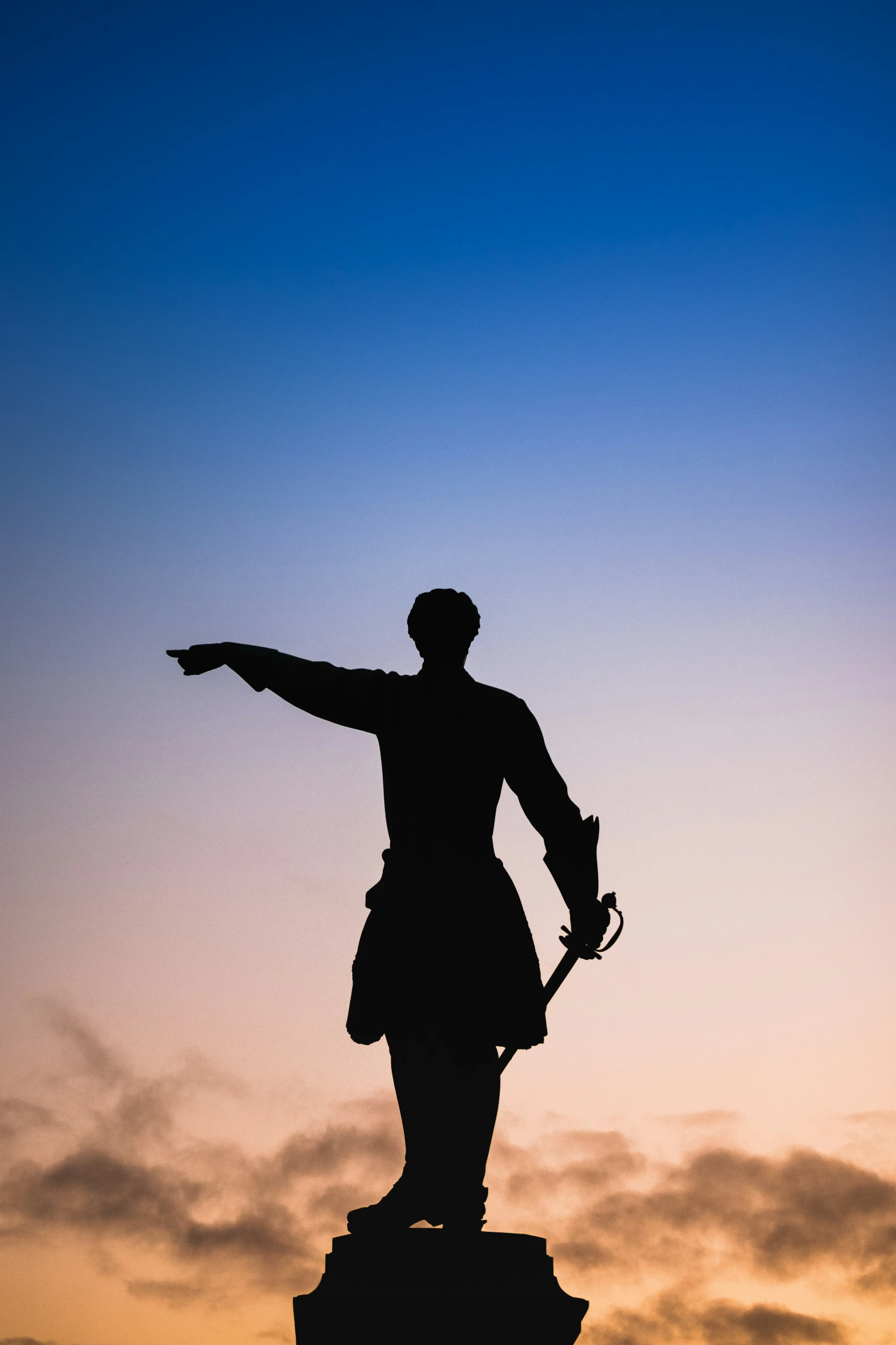 a silhouette of a person with his hand on the top of a statue