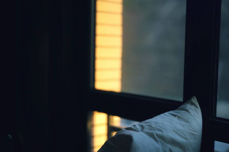 a pillow sitting under a window covered in a blanket