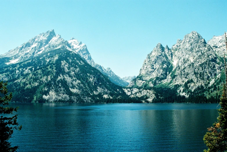 a lake in the middle of some mountains with trees around it