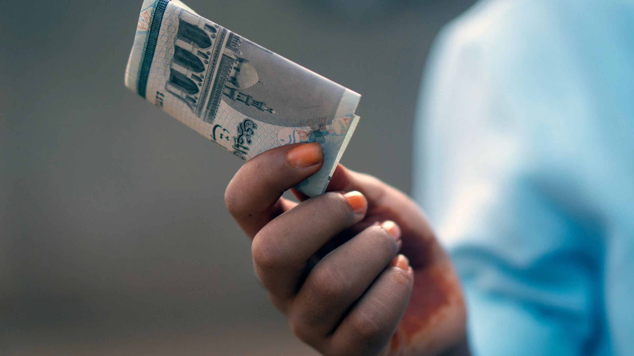 an indian woman holding a roll of cash