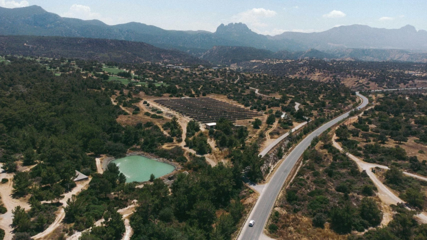 an aerial view of a road surrounded by green trees and mountains