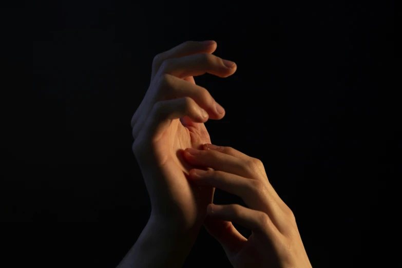 hands reaching out toward each other on dark background