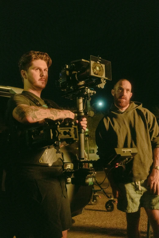two men with one man holding a tripod in front of them