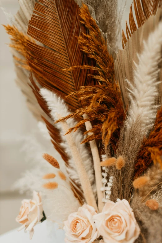 a vase with dried flowers and feathers