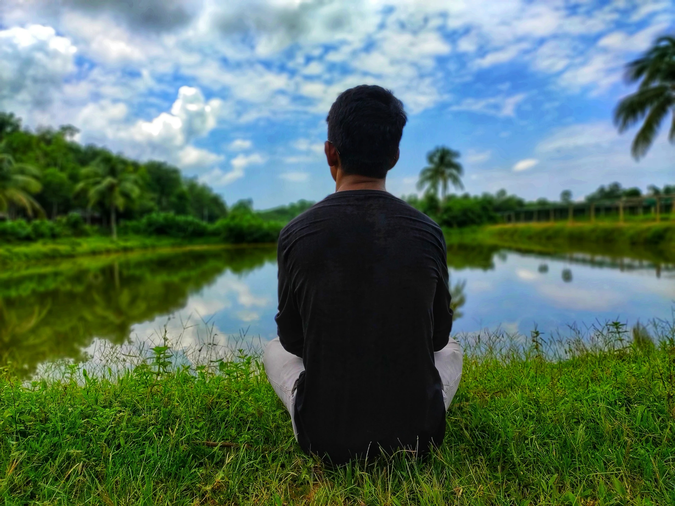 a person sitting on the ground near a lake