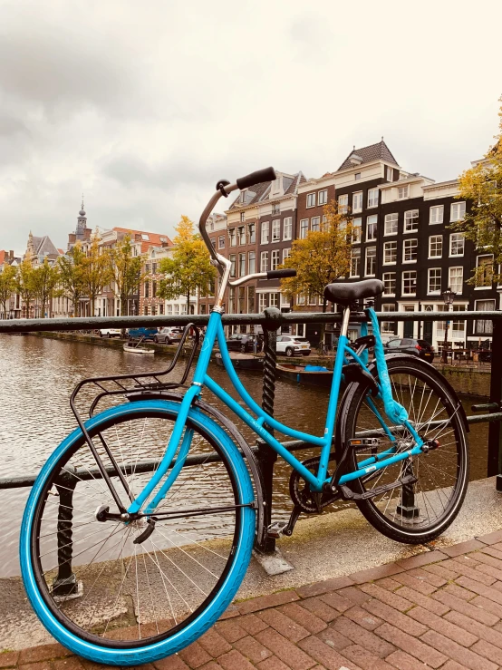 a blue bike is  to a fence near water