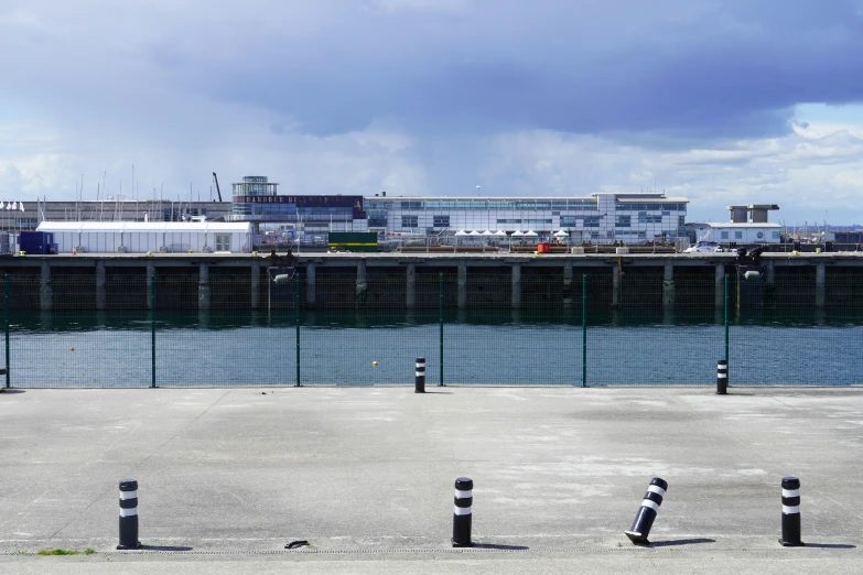 three poles stand in the concrete by a pier