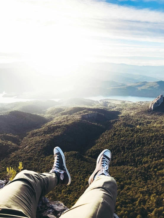 a person is lying down on the edge of a mountain