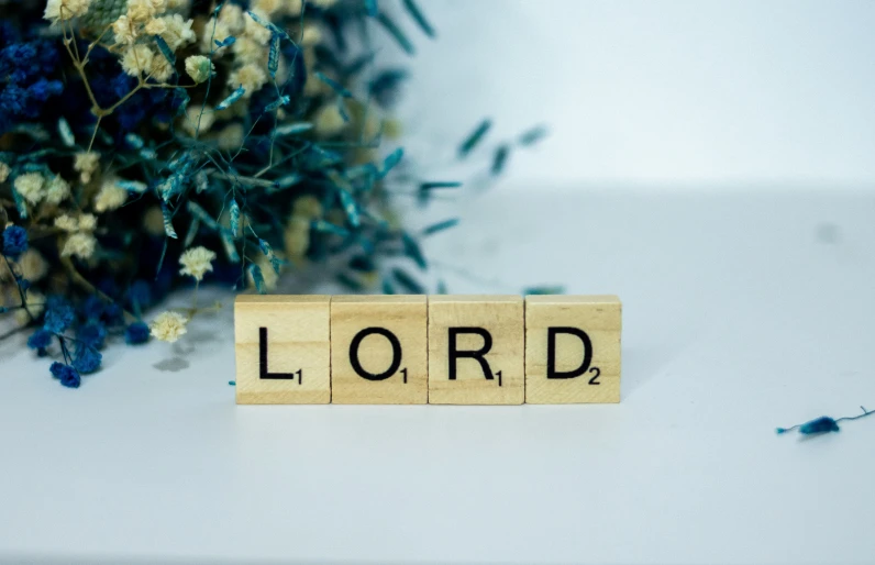 the word lord spelled by scrabbles next to a bouquet of flowers