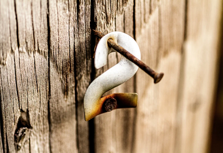 a old, rusted metal hook on an old wooden fence