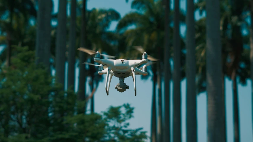 a large propeller flying in front of a forest of trees