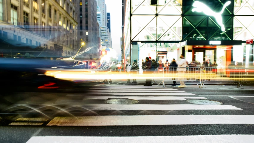blurred pograph of people waiting at a crosswalk in a busy city
