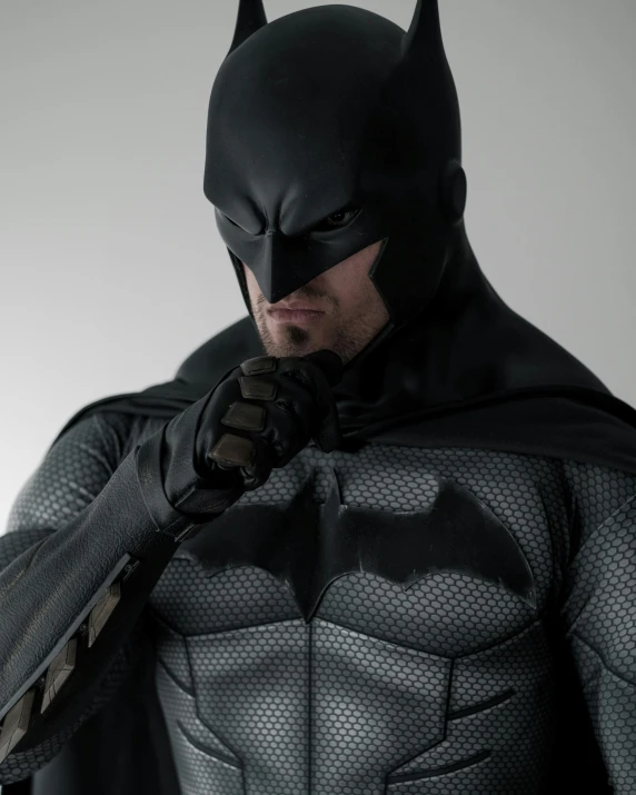 batman standing in black leather armor with gloves