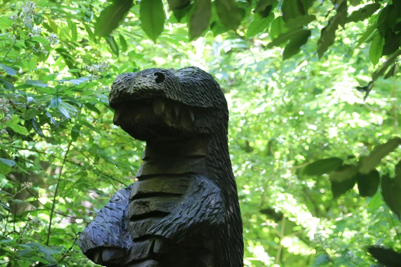 a wooden statue of a dinosaur sitting in the trees