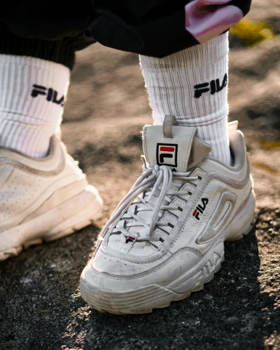 a close up view of the feet and shoe laces of a pair of fila sneakers on concrete