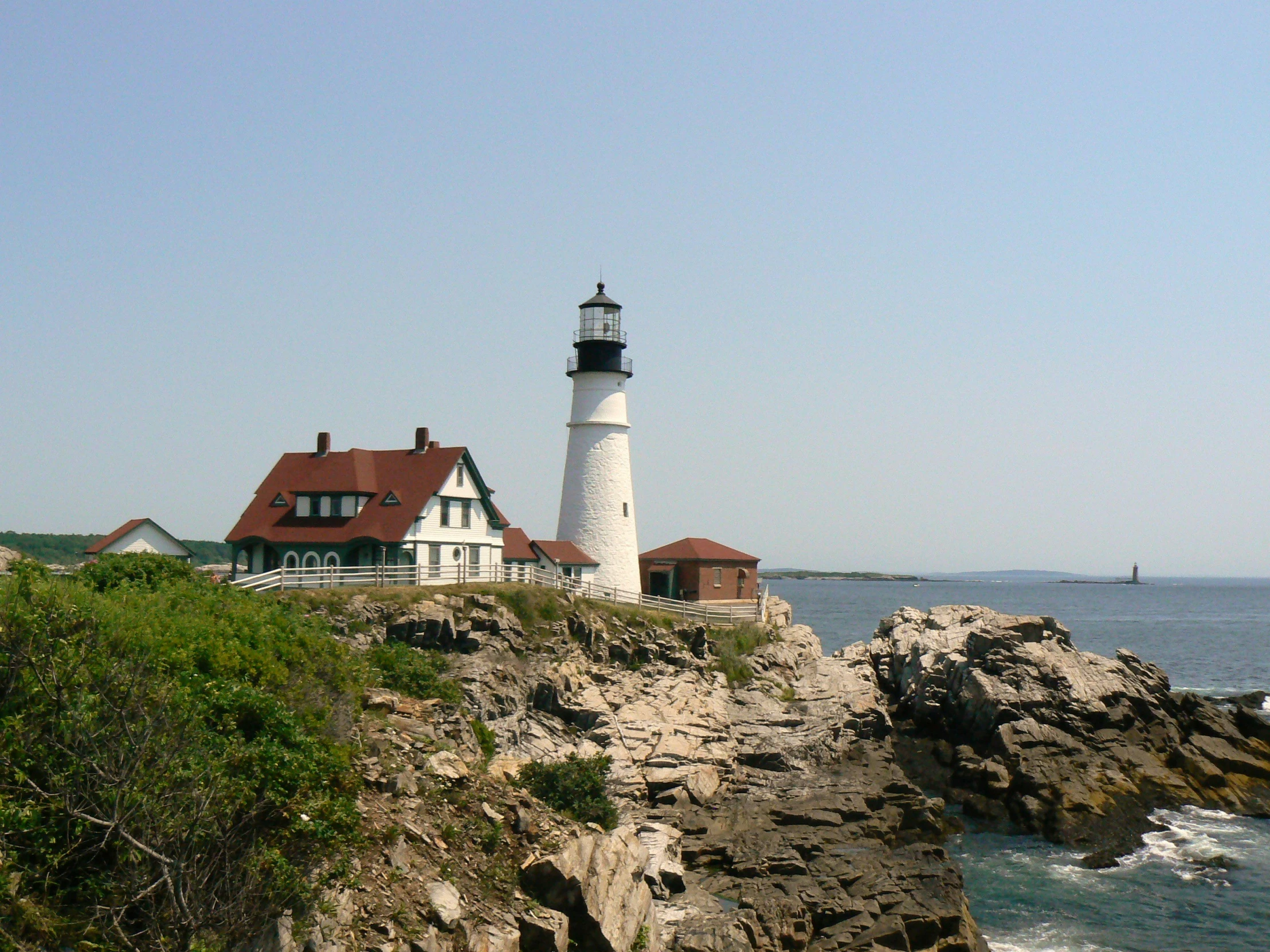 two lighthouses at the top of a cliff near the ocean