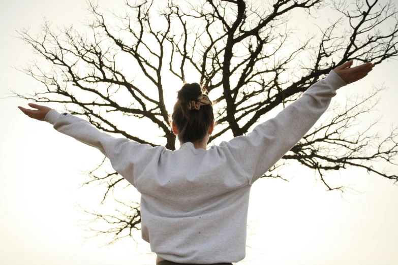 a woman holding her arms out toward the sun