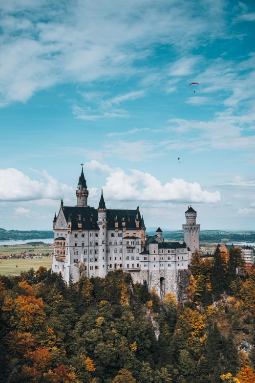 the large castle is set atop a hilltop in an area with tall trees