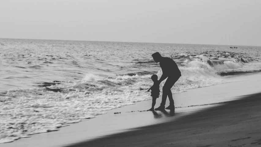 an older woman stands by the ocean while holding a child