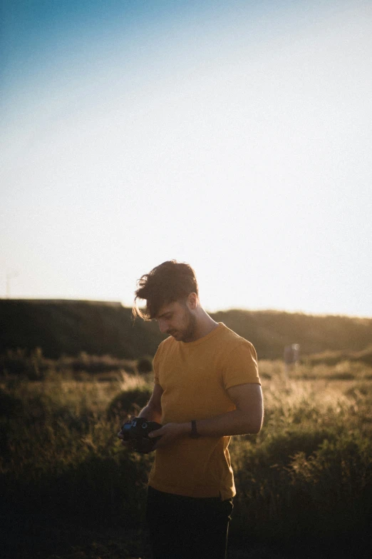 a man standing in a field with his hands in his pockets