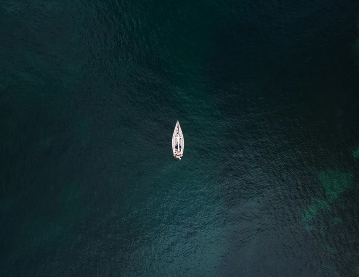 small white boat on calm water off a rocky coastline
