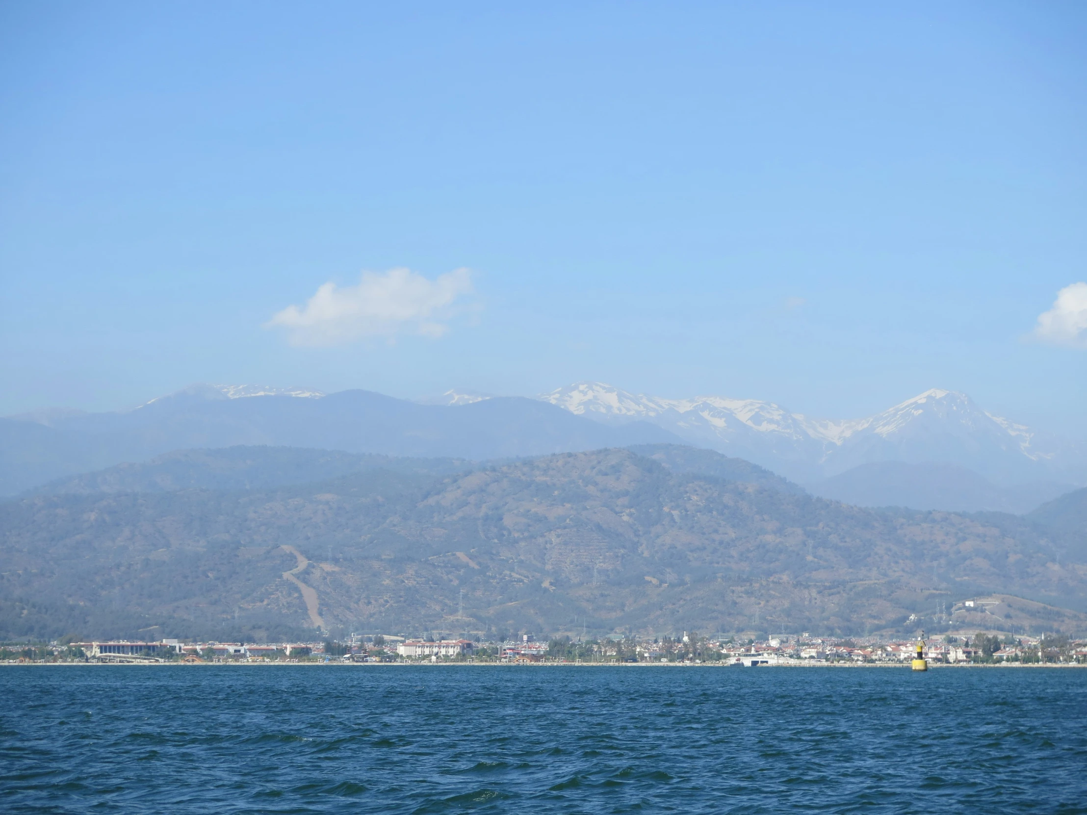 there is mountains and buildings behind the ocean