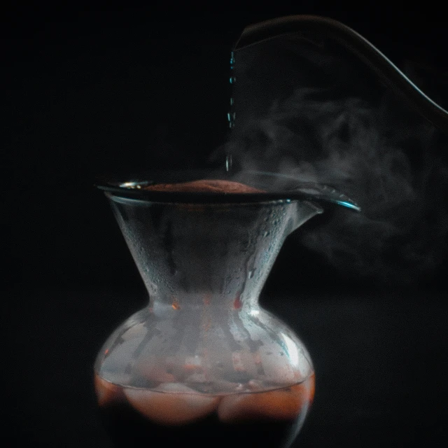 smoke pouring from a glass beakle in the dark