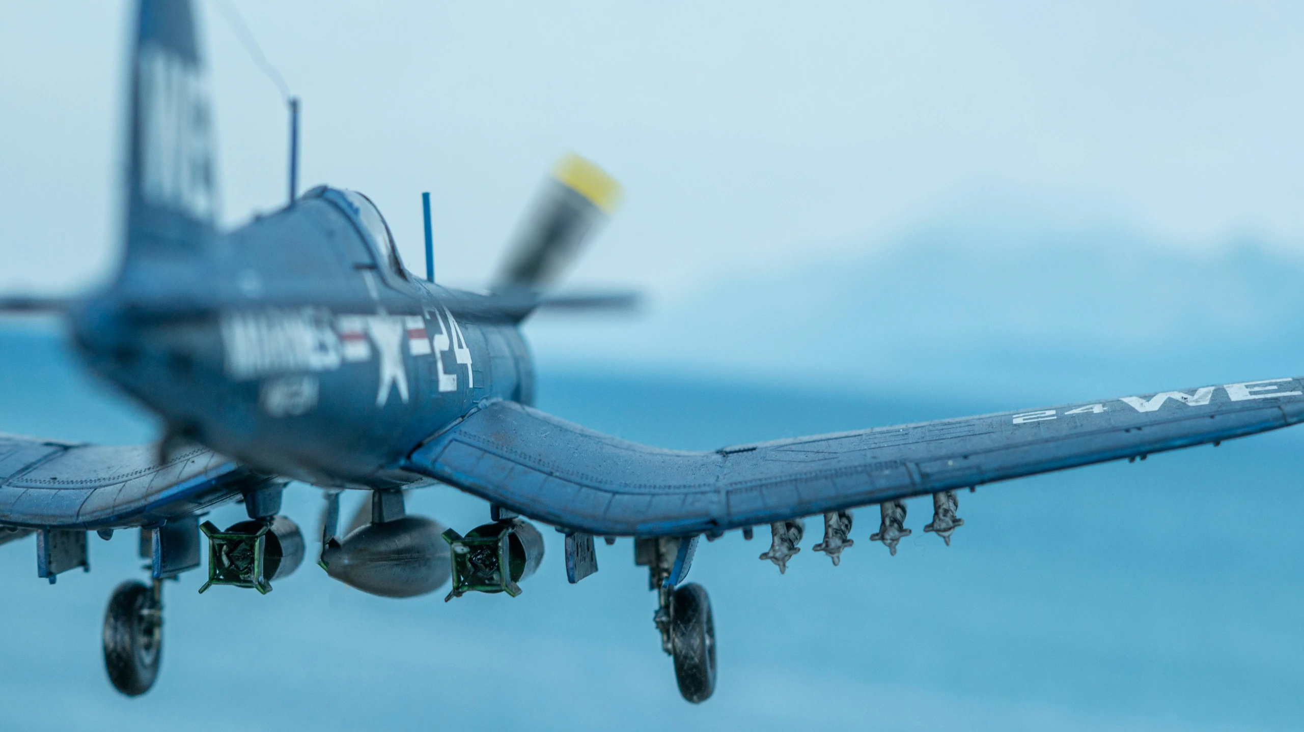 a blue airplane flying above the ocean