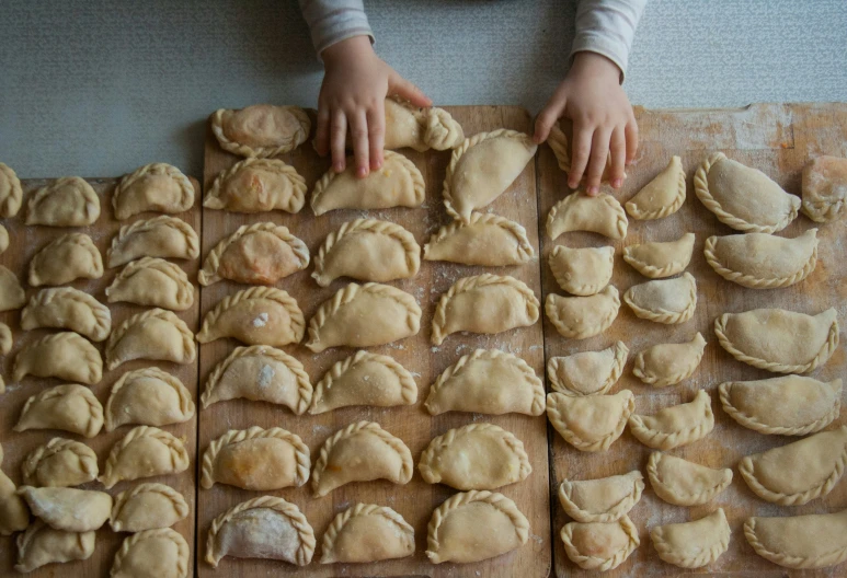 a person rolling dough into pastries on a counter