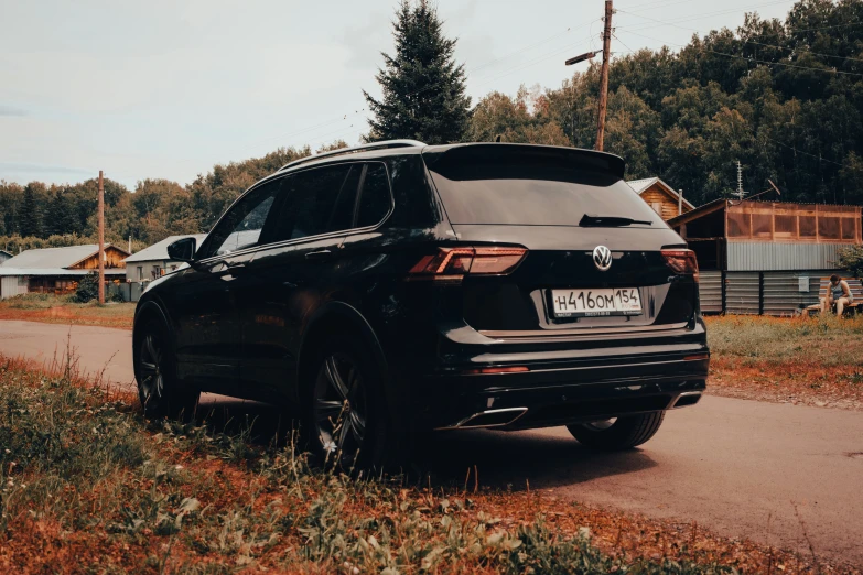 a black suv is parked in the middle of a country road