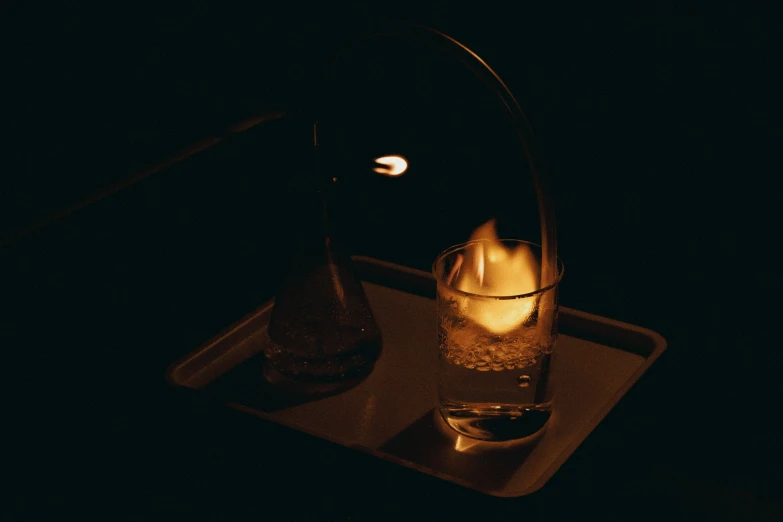 a candle burns in a glass while sitting on a tray