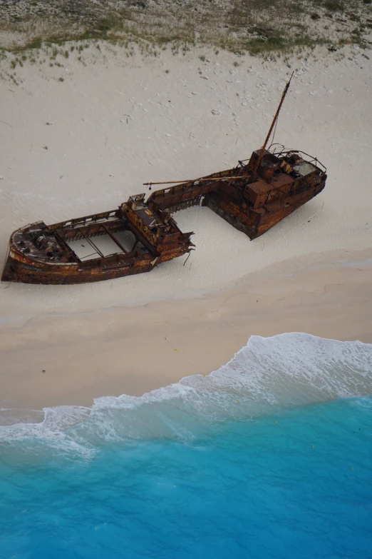 an old rusted wooden boat is on the beach