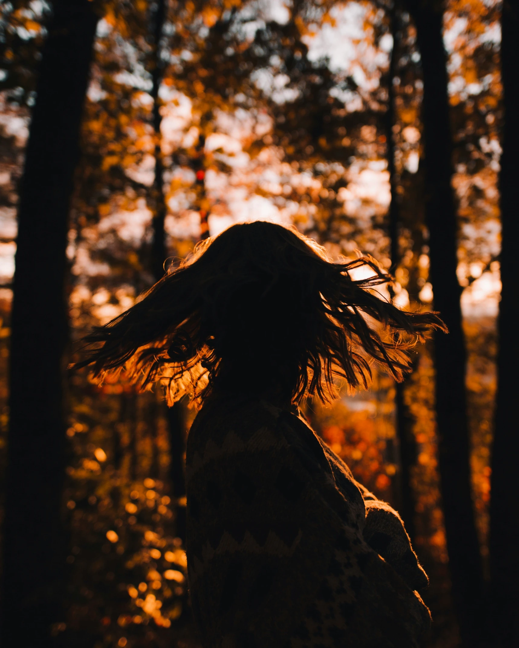 a woman standing in the woods with her hair in the air