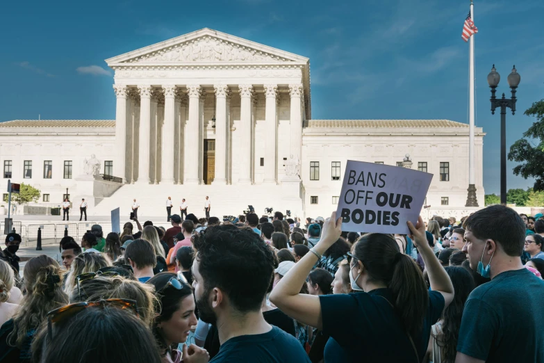 people gathered outside the supreme courthouse holding signs