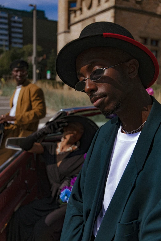 a man wearing a hat standing near other people