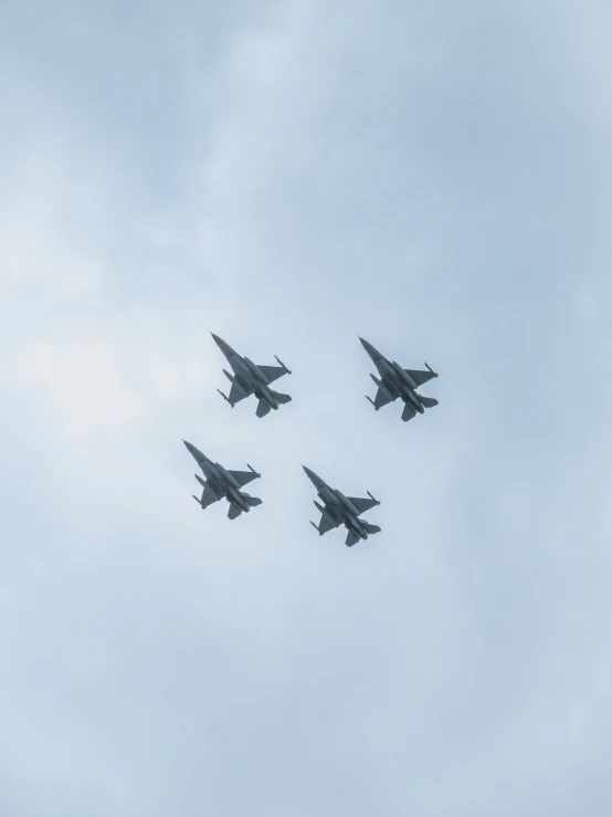 four fighter jets are flying in formation in the sky