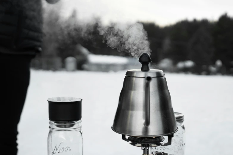 a silver coffee pot on a glass carafe in the snow