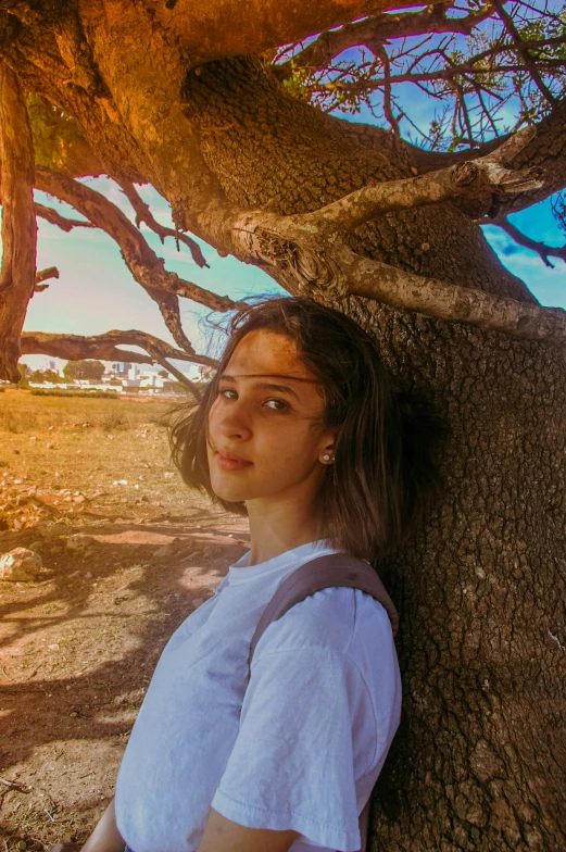 girl leaning against a tree posing for a po