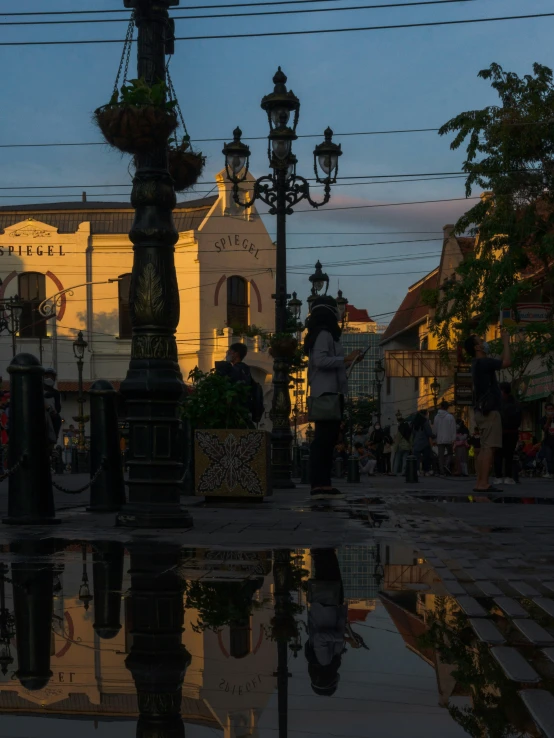 a city center with people walking down the sidewalk at dusk